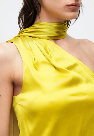 Žltý saténový top s jednoramenným dizajnom, ktorý obsahuje skladané detaily a závesný krčný motýlik. Hladká textúra zdôrazňuje �žiarivú farbu.
