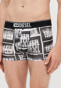Boxers pretos e brancos com um padrão gráfico repetido. Cintura elástica com o logótipo "DIESEL". Tecido macio e elástico. Corte clássico.