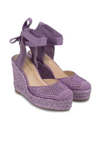 Sandales compensées violettes avec une base en jute tressé, des dessus en tissu texturé, et une bride de cheville décorative avec un noeud. Présente des accents en strass sur le bout.