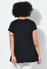 Černý top s krátkým rukávem a rozšířeným lemem, vyrobený z měkké látky, s jednoduchým designem a elegantním střihem.