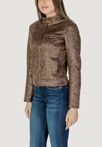 Giacca in finta pelle marrone con colletto alto, chiusura con zip e vestibilità slim. Caratterizzata da tasche laterali e una finitura testurizzata. Abbinata a jeans blu.
