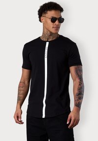 Schwarzes T-Shirt mit kurzen Ärmeln, das einen zentralen weißen vertikalen Streifen mit dem Text "ESTEEM" aufweist. Hergestellt aus glattem Stoff, figurbetontem Design und rundem Halsausschnitt.