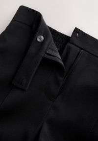 Mustad püksid, millel on nööp ja lukk. Vöökoht sisaldab elastset venivust. Sile kangas ja kohandatud disain.