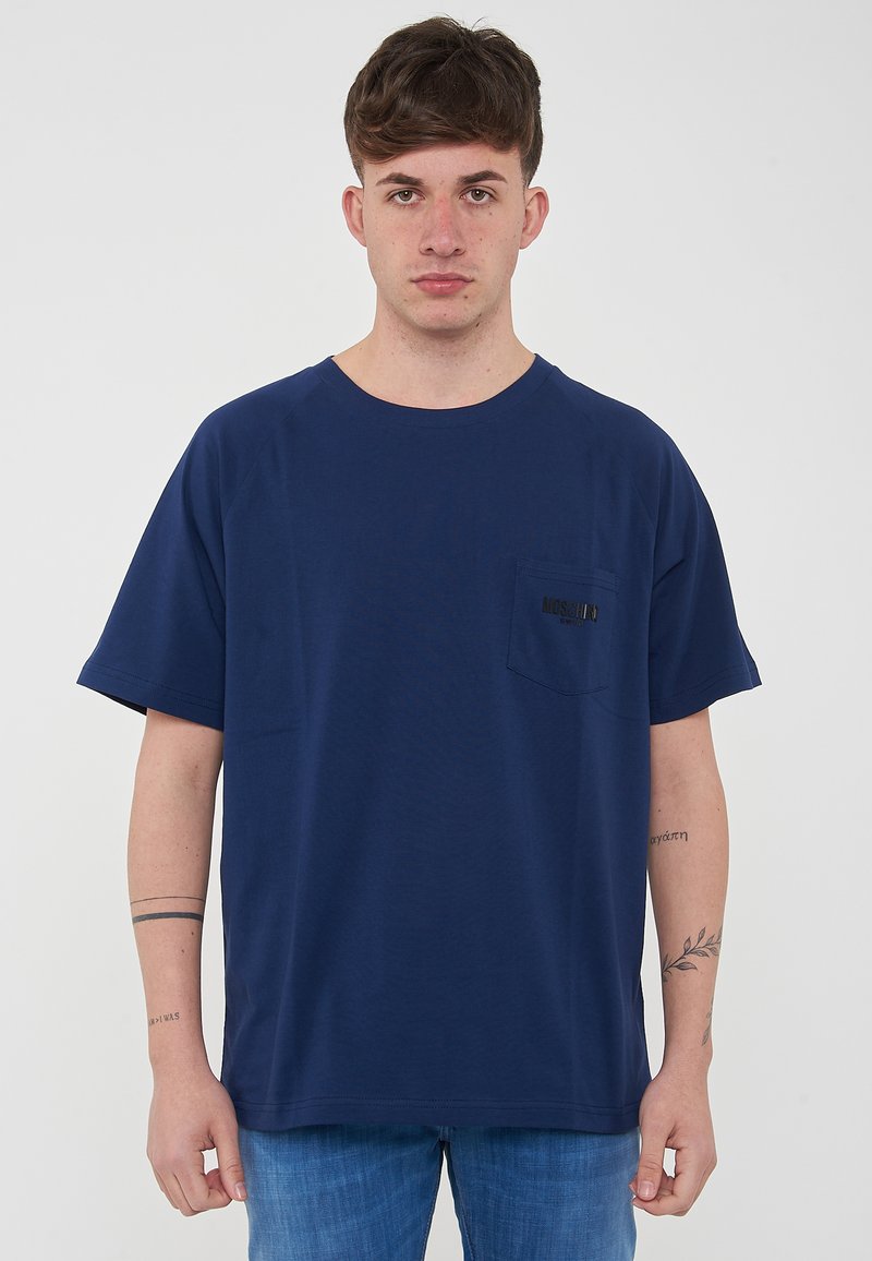 T-shirt a maniche corte di colore blu navy in cotone. Presenta una tasca sul petto con scritte nere. Linea semplice e morbida con scollatura rotonda.