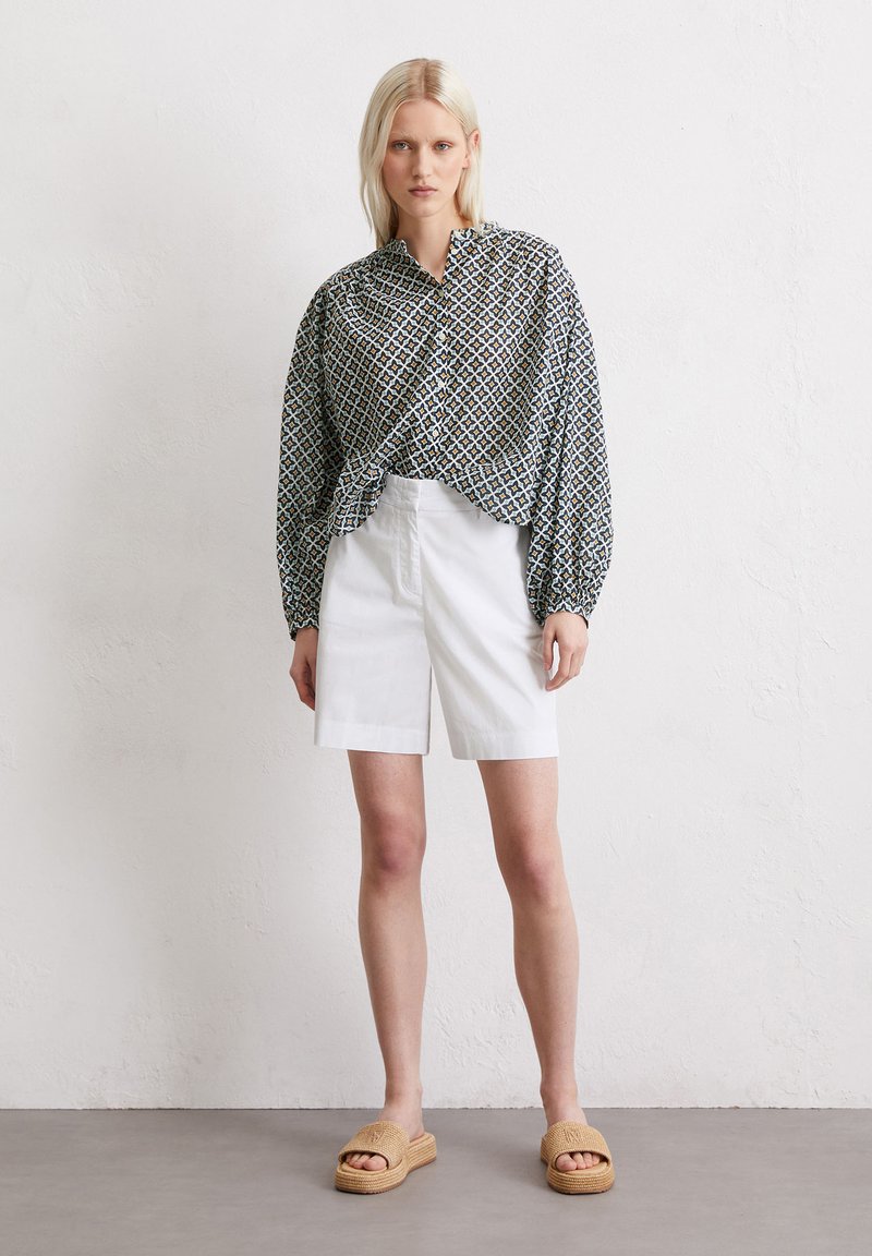 Blusa con motivo, maniche lunghe e frontale annodato, abbinata a pantaloni corti bianchi e sandali in tessuto color nocciola. Tessuto testurizzato e vestibilità rilassata.