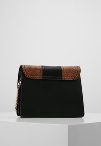 Sac à main en cuir noir avec un rabat texturé à motif serpent marron, une bandoulière chaîne dorée et une forme rectangulaire, présentant des lignes épurées et des détails minimalistes.