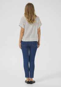 Striped short-sleeve top, light color, loose fit; paired with dark blue skinny jeans, ankle length, slight fading, black flat shoes.