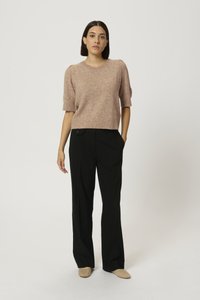 Lys pink strikket sweater med korte ærmer, parret med højtaljede sorte bukser. Båret med beige flade sko med et struktureret design.