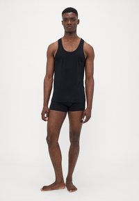 Schwarzes Tanktop und Shorts-Set, aus glattem Stoff. Ärmelloses Design, taillierte Form, und schlicht ohne Muster oder Akzente.
