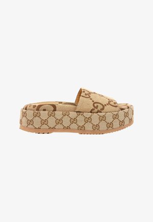 Beige platformsandal med brunt sammenflettet G-mønster og tyk sål, åben tå og bred rem over fronten.