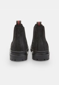 Mustad musta väljakäe nahast kingad tekstuuriga viimistlusega, elastsed külgpaneelid ja kontrastne punane tõmblukk. Kerged kummist tallad haardeks.