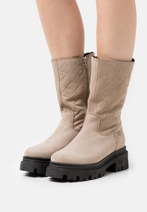 Stivali alla caviglia beige con tomaia trapuntata e suola chunky nera a contrasto. Texture in morbido suede, con zip laterale per una facile calzata.