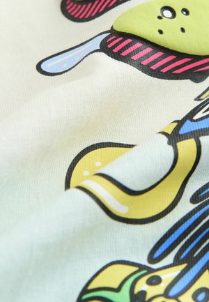 Kokvilnas audums ar krēmkrāsas fona rāda krāsainus karikatūru motīvus, tostarp dzeltenus, zaļus un zilus elementus ar melniem kontūriem.