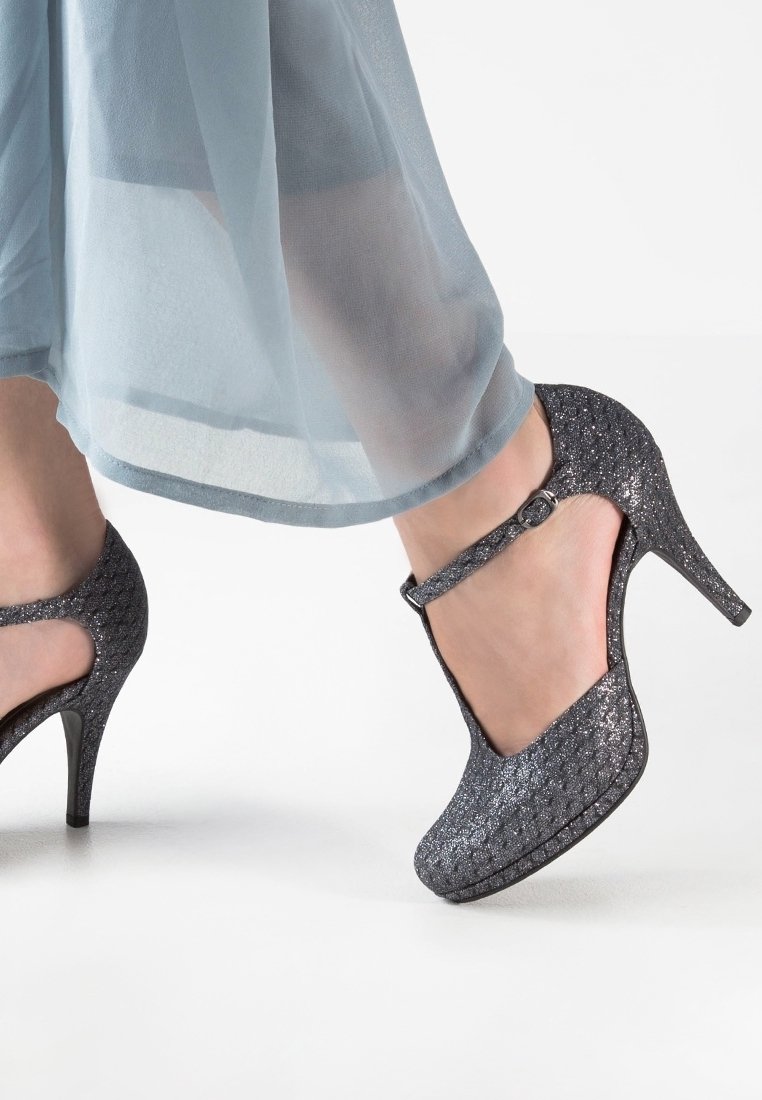 Escarpins Mary Jane en paillettes grises avec une sangle et une boucle, présentant une surface texturée et un talon stiletto effilé.