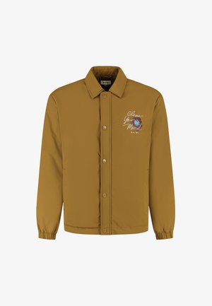 Pruun nööbiga jakk elastsete mansettide ja kraega, millel on valge emberdatud tekst "Selgita Oma Meelt" ning sinise ja pruuni abstraktse kujundusega rinnal.