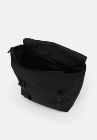 Sac fourre-tout noir en tissu résistant, doté d'un intérieur spacieux, d'une fermeture à glissière supérieure et de doubles anses avec des détails en métal.