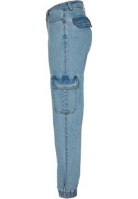 Pantalon cargo en denim bleu clair avec poignets élastiques, poche à rabat latérale sur la cuisse, poche à rabat arrière et passants de ceinture.