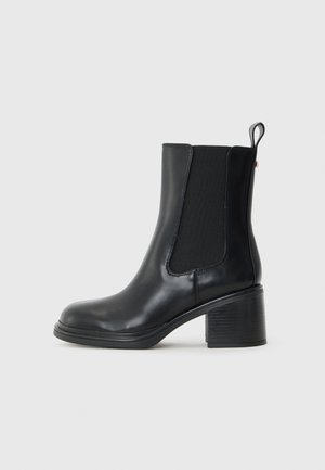Black leather ankle boot with elastic side panels, rounded toe, and a textured block heel. Smooth finish with a subtle sheen.