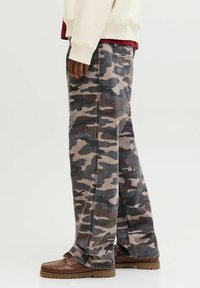 Pantalons cargo en camouflage avec une coupe décontractée, confectionnés en coton. Présentent un mélange de motifs gris, marron et noir, une poche latérale et des détails de couture.