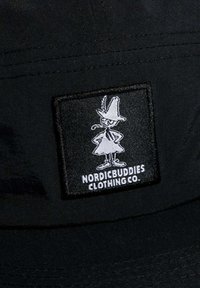 Mustapukuinen hattu, jossa on suorakulmainen brodeerattu tägi, jossa valkoinen hahmo ja tekstinä "NORDICBUDDIES CLOTHING CO." alla.