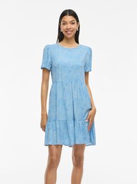 Niebieska sukienka z krótkim rękawem, z okrągłym dekoltem, z warstwowym falbankowym dołem oraz wzorem w kropki. Wykonana z lekkiego materiału w luźnym kroju.