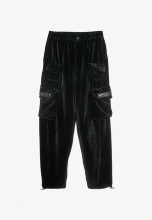 Pantalones de pana negra con cintura elástica, múltiples bolsillos frontales y puños con cremallera. Presentan una textura suave y acanalado vertical.