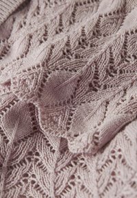 Stickad tröja i mjuk lavendel med ett bladmönster. Texturen verkar skir och visar upp intrikata öppenarbeten mellan de stickade sektionerna.