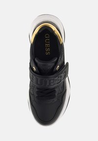 Baskets Guess en noir et blanc avec accent doré au talon, sangle Guess embossée et lacets noirs, vues de dessus.