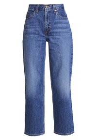 Siniset farkut korkealla vyötäröllä, suorilla lahkeilla ja kuluneilla alueilla. Klassinen viiden taskun malli ja metallinen napin suljin.