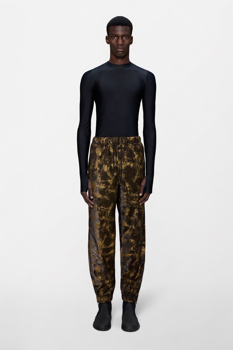 Μαύρο μακρυμάνικο τοπ συνδυασμένο με καφέ τζόγερς με σχέδιο tie-dye. Οι τζόγερς έχουν ελαστική μέση και ρεβέρ στα τελειώματα. Μαύρα παπούτσια συμπληρώνουν το σύνολο.