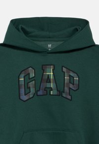 Hoodie verde escuro com bolso canguru frontal, apresentando as letras "GAP" em padrão de xadrez azul e verde no peito.