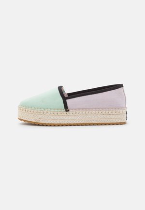 Zapato estilo espadrille con parte superior de lona verde menta y púrpura claro, ribete negro y suela de plataforma de yute trenzado con acabado texturizado.