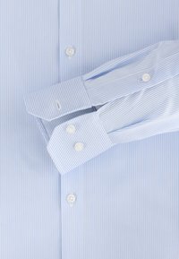 Lichtblauw overhemd met smalle witte strepen. Heeft een klassieke kraag, knoopmanchetten en witte knopen. Glad, fijn geweven stof.