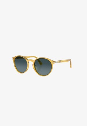 Gafas de sol de montura redonda amarilla con lentes oscuros de color gris. Las patas de plástico transparente presentan detalles sutiles. Diseño ligero para mayor comodidad.