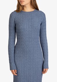 Vestito in maglia di colore azzurro chiaro, caratterizzato da una texture a costine, scollatura a girocollo e maniche lunghe con polsini aderenti.