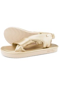 Gold-toned flip-flop sandals feature a sleek, smooth synthetic upper with crisscross straps and a cushioned, textured outsole.