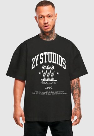 Juodas laisvas marškinėliai su baltu tekstu ir grafiniu dizainu. Pavyzdžiui, yra „2Y STUDIOS“ ir „Worldwide 1992“ šūkiai, o priekyje yra trys figūros.