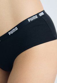Black cotton bikini underwear featuring an elastic waistband with white "PUMA" branding. Smooth texture and fitted design.