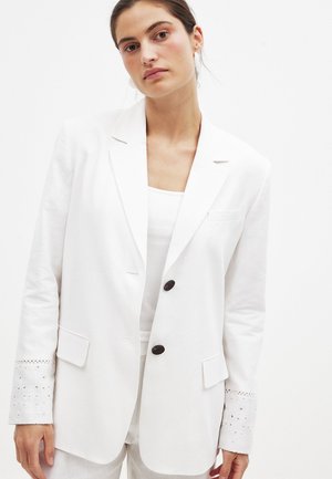 White linen blazer featuring two black buttons, notched lapels, and eyelet-detail cuffs. Tailored fit with side pockets.