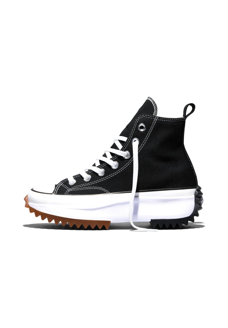 Black high-top sneaker with white laces, thick white midsole, and brown and black jagged rubber outsole viewed from the side.
