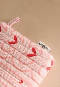 Gequilted pannenlap in roze stof, met een wit loofpatroon en rode accenten. Inclusief een ophanglus en een logo-label.