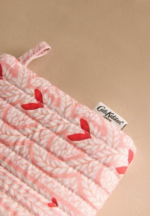 Pâlnie de oală cu quilt în material roz, având un model de frunze albe cu accente roșii. Include o buclă pentru agățat și un etichetă cu logo.
