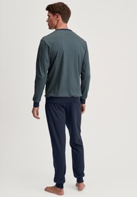 Blau gemustertes Langarmoberteil mit geometrischem Design, kombiniert mit einfarbigen marineblauen Hosen mit elastischen Bündchen und Taillenbund, aus weichem Stoff gefertigt.
