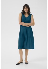 Teal sleeveless dress with a V-neck and textured fabric, featuring a pleated skirt and decorative stitching along the neckline.