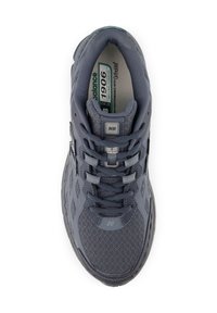 Chaussure de sport grise avec tige en maille hexagonale, languette rembourrée, lacets et écusson logo sur le côté. Semelle en caoutchouc notable pour une excellente traction.