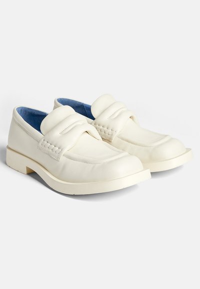 White leather loafers with a rounded toe, padded strap across the vamp, and a textured accent. Light blue inner lining and thick outsole.