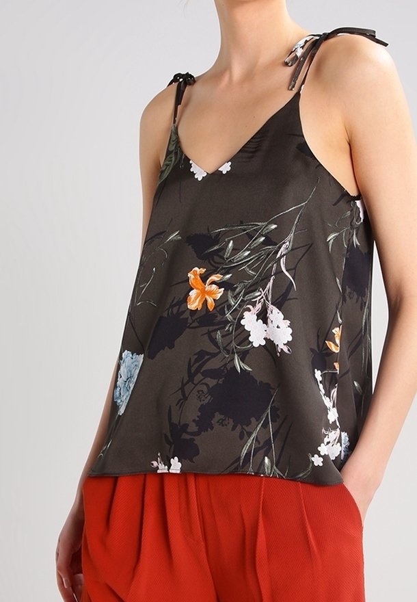 Dark floral tank top in lightweight fabric with adjustable straps, featuring orange and white flowers on a black background, paired with red pants.
