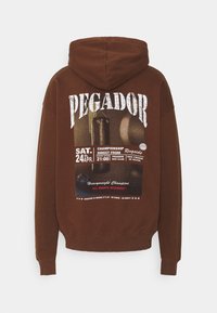 Hnědá mikina s velkým grafickým potiskem na zádech, který obsahuje text, boxerskou tematiku a datum. Měkká textura a volný střih.