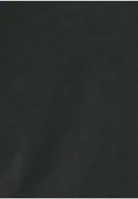 En grupp människor står i ett modernt kontorsutrymme och diskuterar arbete med bärbara datorer och dokument på ett glasbord.