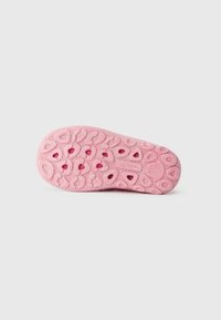 Rosa gummi såle med teksturert grep, med hjerte- og bølgemønstre, samt en lett glitrende effekt. Merket "superfit" er preget.